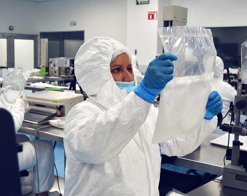 Inspector in cleanroom reviewing primary pouch packaging for vascular guidewires